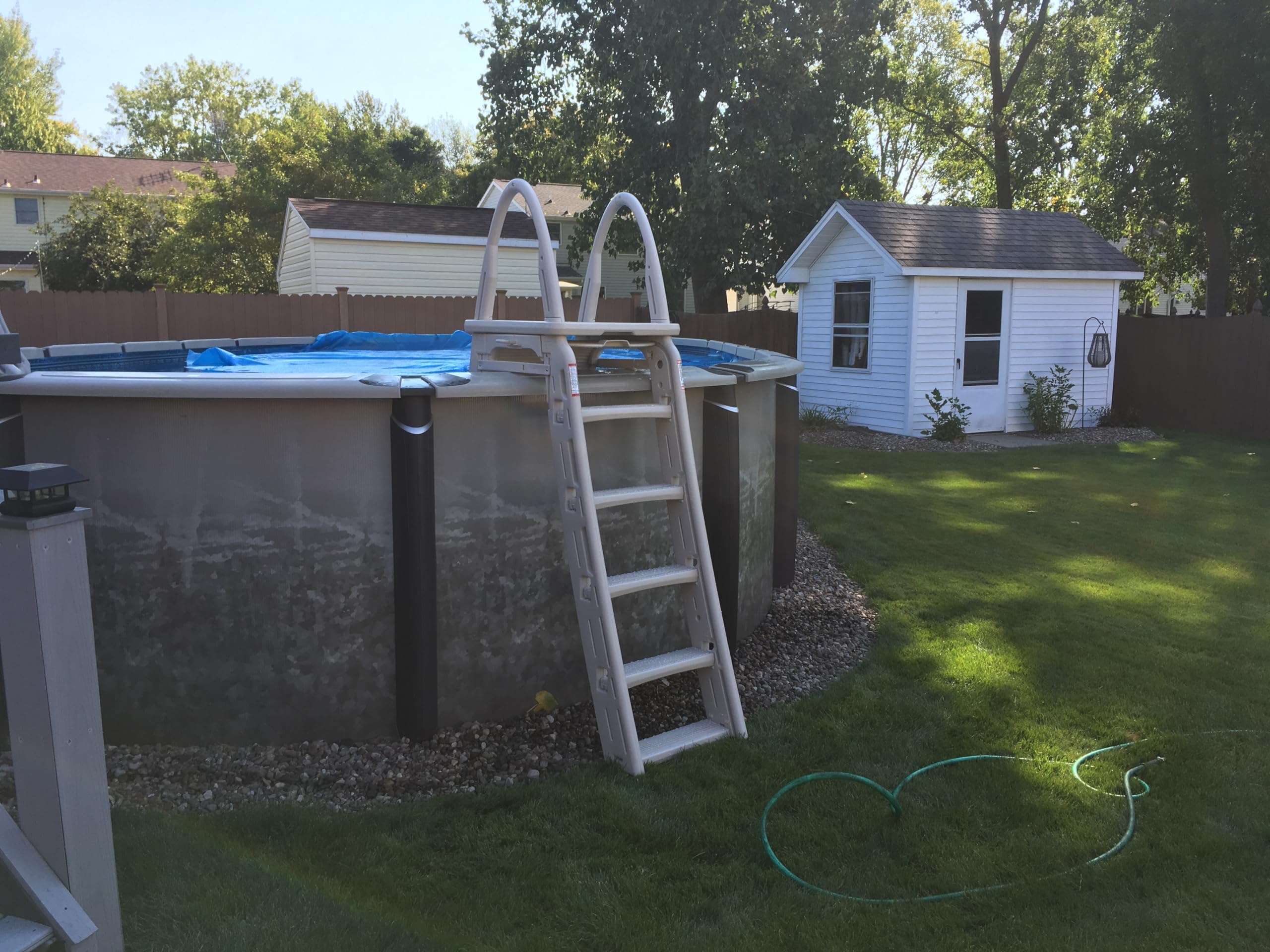 Confer Roll-Guard ladder installed on a grey resin round above-ground pool in a backyard