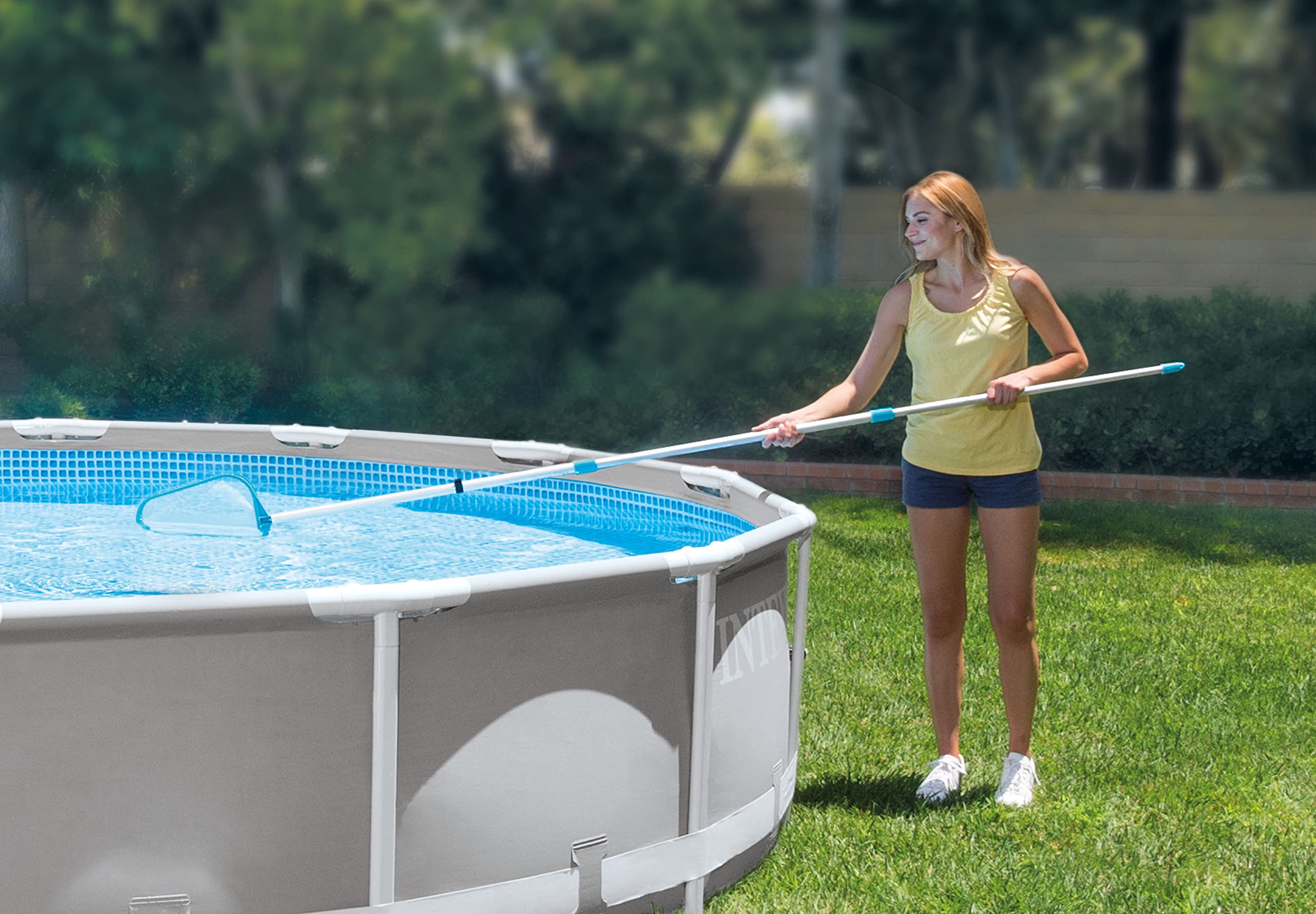 Woman skimming the surface of a frame above-ground pool with the Intex skimmer net on the pole