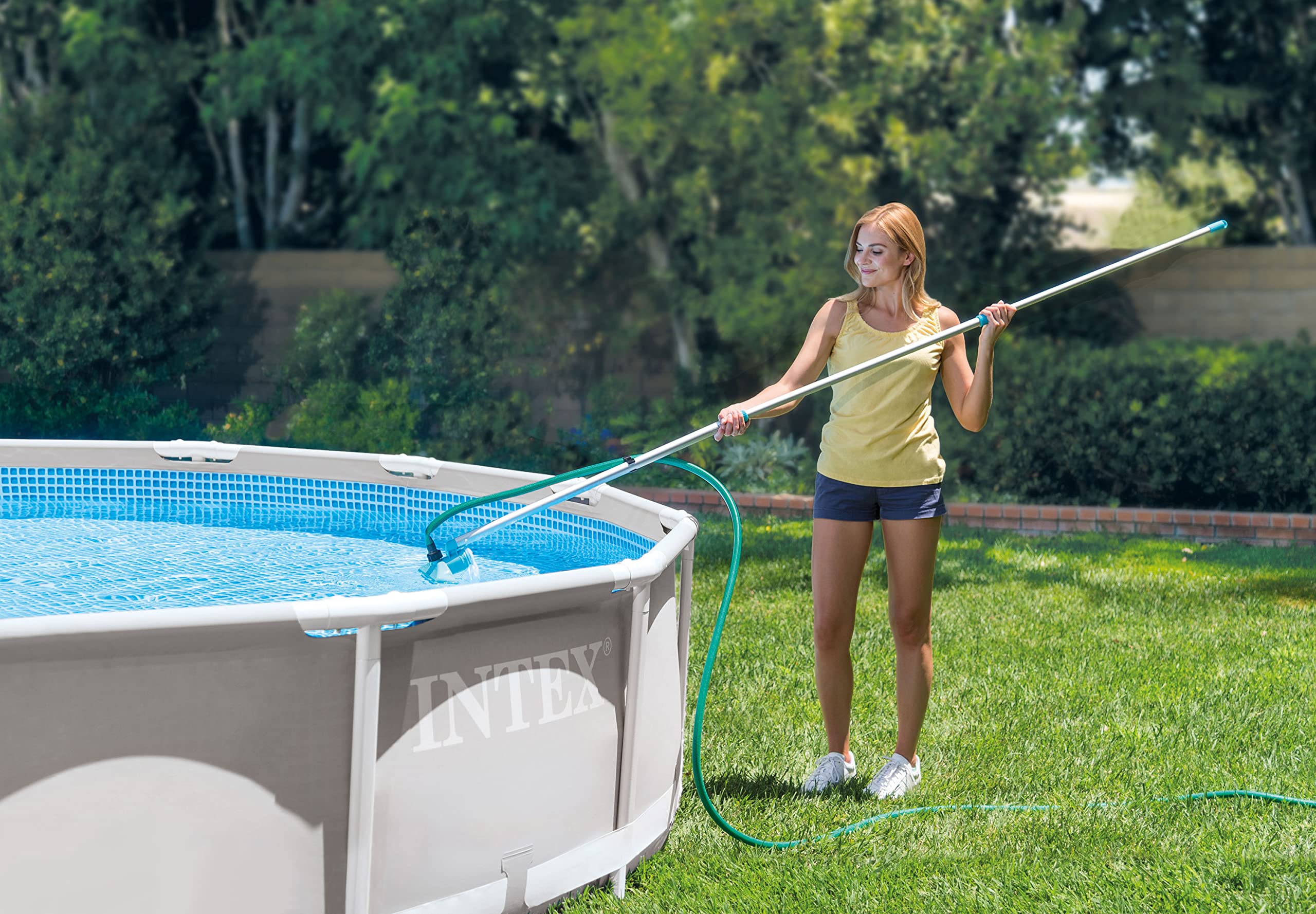 Woman vacuuming a metal-frame above-ground pool with the Intex pole and garden hose
